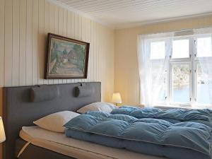 um quarto com uma grande cama azul e uma janela em Holiday home LYNGØR 
