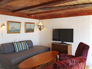 uma sala de estar com um sofá e uma televisão de ecrã plano em Holiday home LYNGØR 