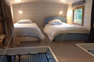 2 camas en una habitación pequeña con ventana en Mini maison tiny house et son bain nordique, en Figeac