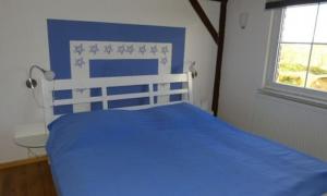 Cama azul en habitación con ventana en Ferienhaus Luppath, en Poseritz