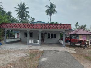 une petite maison blanche avec un toit rouge dans l'établissement Muslim Nur Homestay, à Kepala Batas