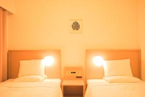 - deux lits dans une chambre avec deux lumières sur les deux dans l'établissement Smile Hotel Okinawa Naha (Tomari Port), à Naha