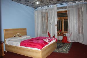 a bedroom with a bed with a red blanket on it at Rakaposhi Amin Hotel & Restaurant Pissan Hunza Nagar Gilgit Baltistan in Gilgit