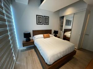 Dormitorio pequeño con cama y espejo en Apartamento en Lobby33 en Guadalajara
