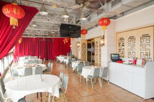 Warwick Hotel Cheung Chau في هونغ كونغ: مطعم بطاولات بيضاء وكراسي وستائر حمراء