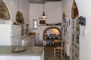 a kitchen with a white refrigerator and a table at Traditional Tinos Olive Mill House in Khatzirádhos