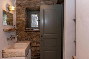 a door leading into a bathroom with a sink at Traditional Tinos Olive Mill House in Chatzirados +37 photos