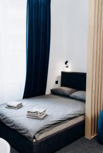 a bed with blue curtains and two towels on it at RESA apart - нові smart-квартири біля річки in Uzhhorod
