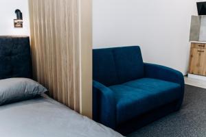 um quarto com uma cadeira azul ao lado de uma cama em RESA apart - нові smart-квартири біля річки em Uzhhorod
