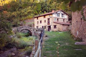 une ancienne maison en pierre dans un champ avec un pont dans l'établissement Posada de Urreci, à Aldeanueva de Cameros