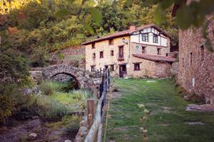 una vieja casa de piedra en un campo con un puente en Posada de Urreci, en Aldeanueva de Cameros