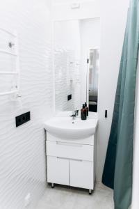 een witte badkamer met een wastafel en een spiegel bij RESA apart - нові smart-квартири біля річки in Oezjhorod