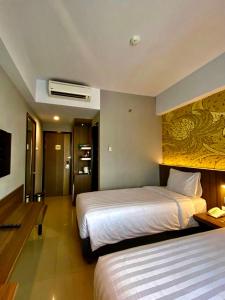 een hotelkamer met 2 bedden en een televisie bij Unisi Hotel Malioboro - Jogja Syariah in Yogyakarta