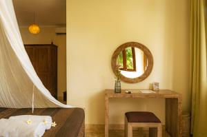 a bedroom with a bed and a mirror and a table at Ecosfera Hotel & Spa in Canggu