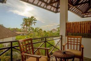 a balcony with two chairs and a view of trees at Ecosfera Hotel, Yoga & Spa in Canggu