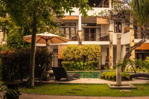 an umbrella and a chair in front of a building at Ecosfera Hotel & Spa in Canggu