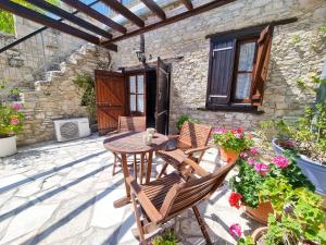 a patio with a table and chairs and flowers at Poseidon's Pool Paradise in Skarinou