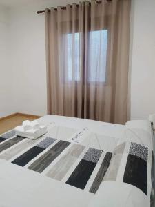ein Bett mit einer schwarzen und weißen Bettdecke und einem Fenster in der Unterkunft NUESTRA SEÑORA DEL PINAR 