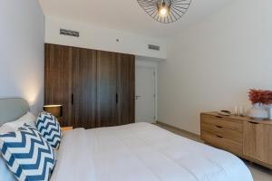 a bedroom with a white bed and a wooden cabinet at Cozy and Spacious l Big Terrace in Dubai
