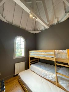 two bunk beds in a room with a window at DOMAINE DES PEYRIES - Chambres et table d'hôtes in Saint-Barthélémy-dʼAgenais