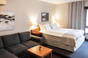 Habitación de hotel con cama y sofá en Frøken Skjolds Hotel Lyngengården, en Mosjøen