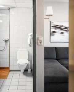 a bathroom with a couch and a toilet at Frøken Skjolds Hotel Lyngengården in Mosjøen