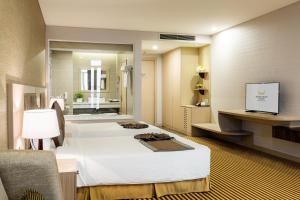 ニャチャンにあるMuong Thanh Luxury Khanh Hoaのベッド2台と鏡が備わるホテルルームです。