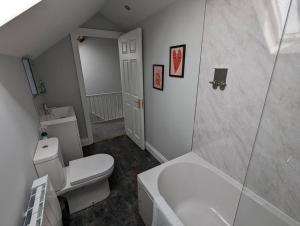 La salle de bains est pourvue d'une douche et de toilettes blanches. dans l'établissement 31 High Street - Modern & Stylish 2-bed Apartment - inc parking, à Husbands Bosworth