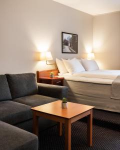 モーシェーンにあるFrøken Skjolds Hotel Lyngengårdenのベッド、ソファ、テーブルが備わるホテルルームです。