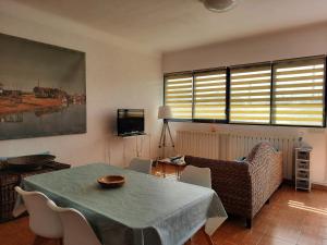 ein Wohnzimmer mit Tisch und Stühlen und einem Fernseher in der Unterkunft Gite la Nouette in La Tremblade