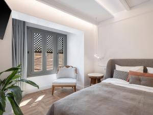 sypialnia z łóżkiem, krzesłem i oknem w obiekcie Ionas Boutique Hotel w Chanii