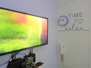 uma televisão de ecrã plano numa parede com um relógio em NEAREST MALL of ASIA Resort-facing 1BR fast wifi em Manila