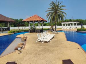 a swimming pool with white chairs and a gazebo at Seabreeze 145 by malai in Rayong