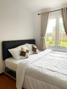 a bedroom with a large white bed with a window at Villa Royal Arois Syariah Dekat Jatim Park 3 in Tlekung