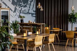 uma sala de jantar com mesas, cadeiras e plantas em Aalborg Airport Hotel em Aalborg