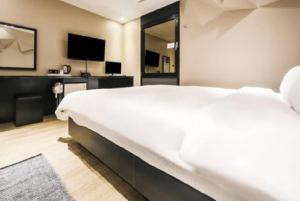 Hotel Cullinan jongno في سول: غرفة نوم بسرير ابيض كبير وتلفزيون