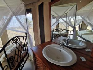 een badkamer met een wastafel en een spiegel bij Serengeti Wildebeest Camp in Banagi