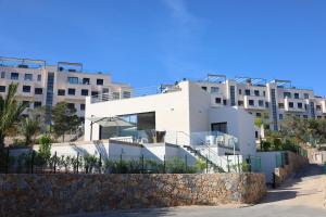 duży biały budynek z kamienną ścianą w obiekcie Deluxe VILLA LAVANDA Las Colinas DEHESA DE CAMPOAMOR with HEATED POOL w mieście Campoamor