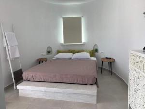 1 dormitorio blanco con 1 cama y 2 mesas en Thronos en Vlychada