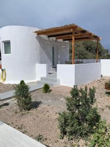 une maison blanche avec des escaliers et un toit en bois dans l'établissement Thronos, à Vlychada