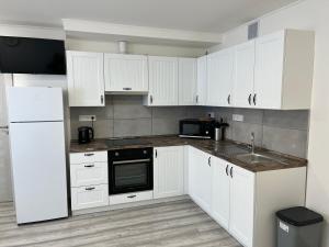 a kitchen with white cabinets and a sink at Kozákov Apartmány - druhé patro 