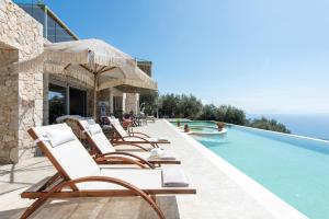 a row of chaise lounge chairs next to a swimming pool at Summerwine Luxury Villa Sea View Private Pool in Spartýlas
