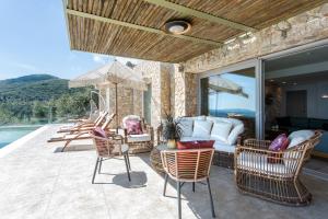 un patio con sedie e un divano sul balcone. di Summerwine Luxury Villa Sea View Private Pool a Spartýlas