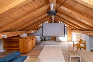 salon z dużym ekranem i drewnianym sufitem w obiekcie Casa Narciso w mieście Rocca Pietore