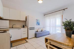 a kitchen with white cabinets and a table with a blue couch at Sea Breeze Apartments, beachfront location in Skála Foúrkas