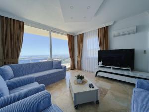 a living room with blue couches and a flat screen tv at Apollon Apartment in Kalkan