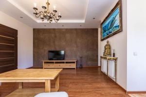ein Wohnzimmer mit einem Tisch und einem TV in der Unterkunft Baltikalnio apartamentai Klaipėdos centre! in Klaipėda
