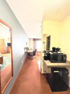 a room with a kitchen with a microwave on a counter at Super 8 by Wyndham Whitecourt in Whitecourt