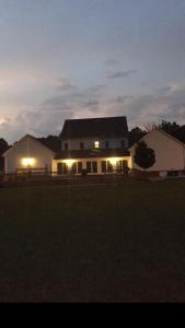 una gran casa blanca con luces encendidas por la noche en MooreField Suites Greensboro East, en McLeansville