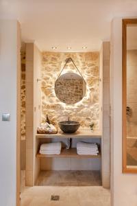 uma casa de banho com um lavatório e uma parede de pedra em Alonion Apartments em Yerakianá